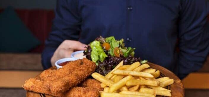 Waiter Serving a Fried Chicken and French Fries on the Wooden Plate